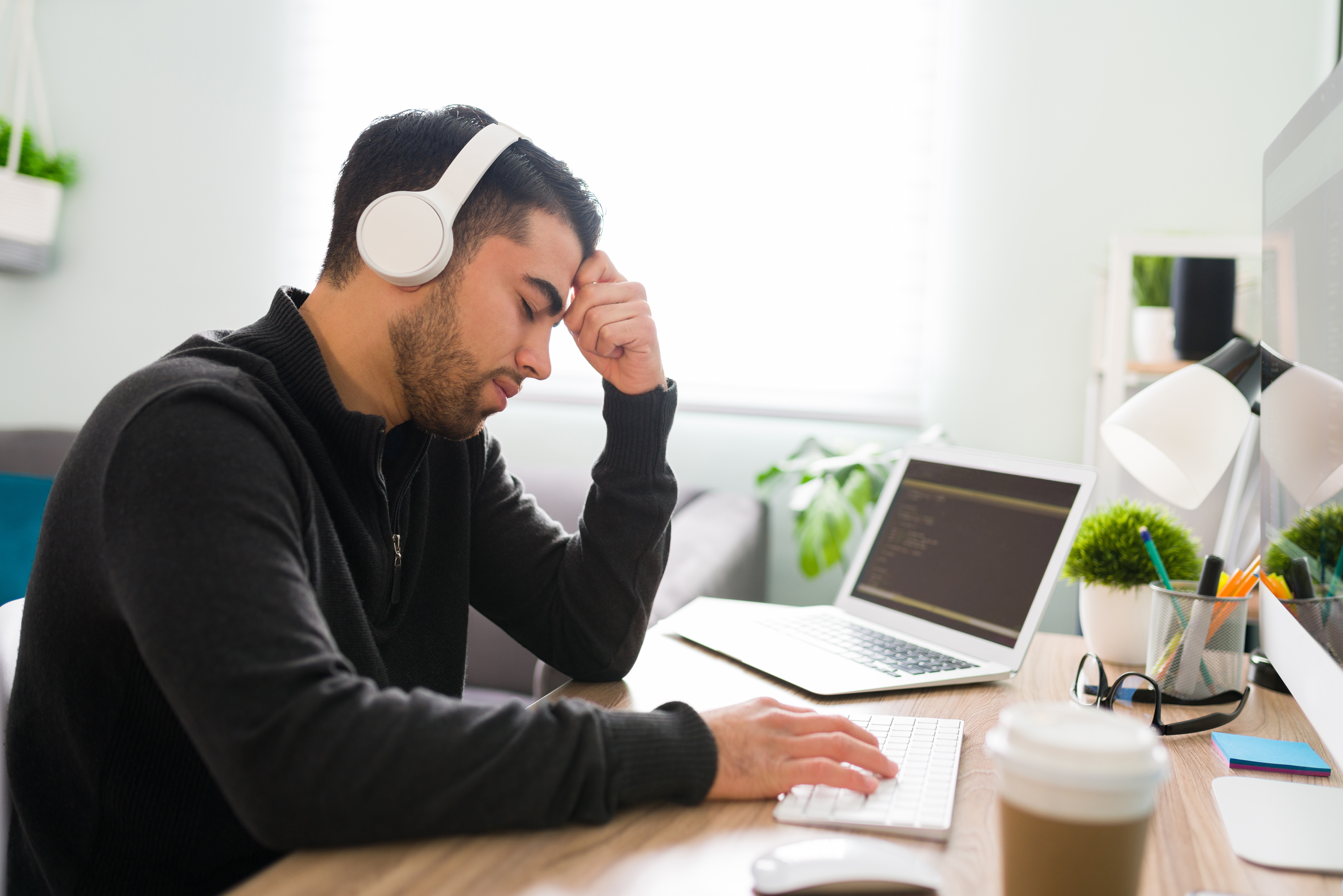 Man with head in heads at the computer screen.