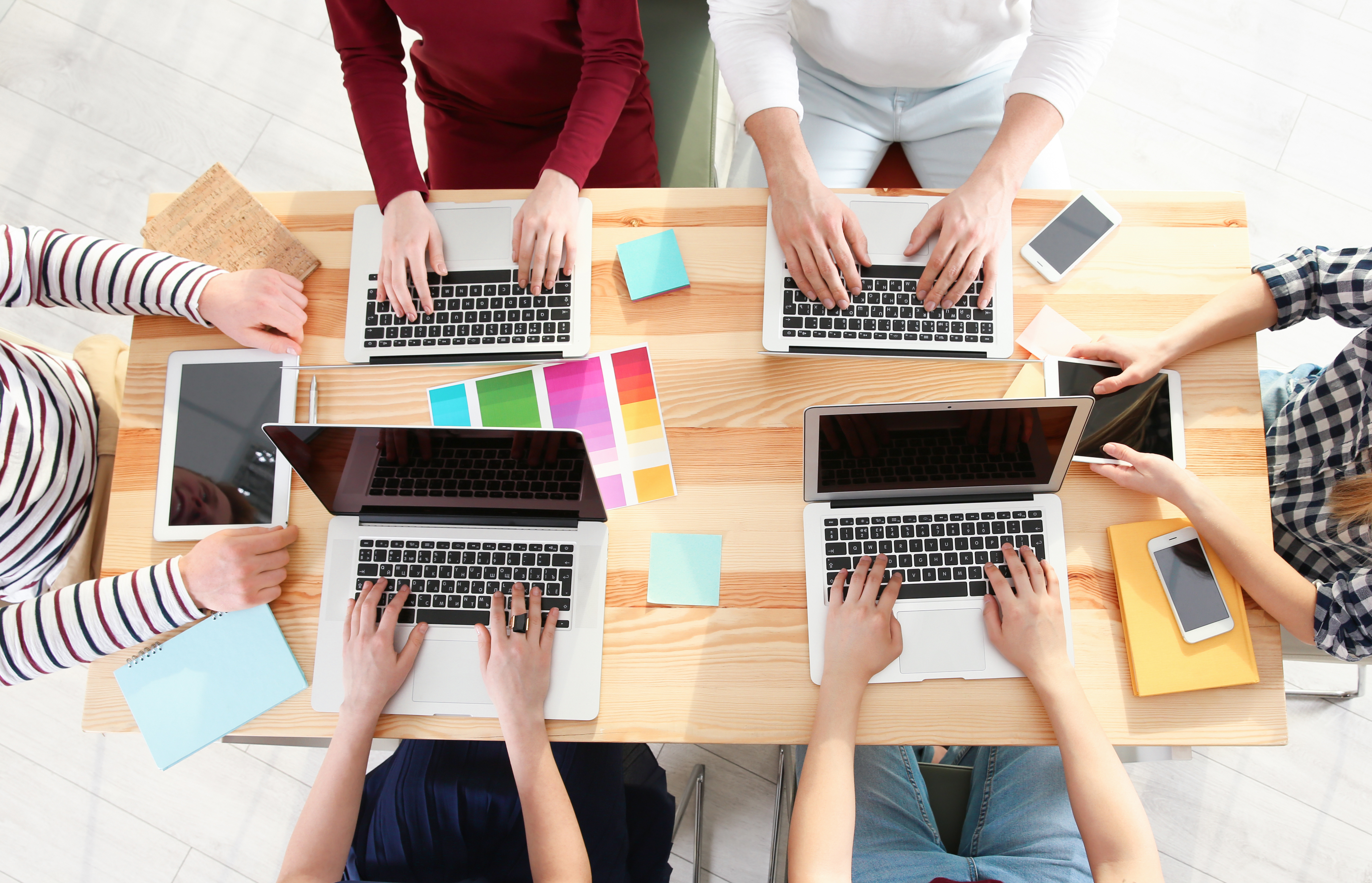 Group of people sitting at a table with laptops and sticky notes.